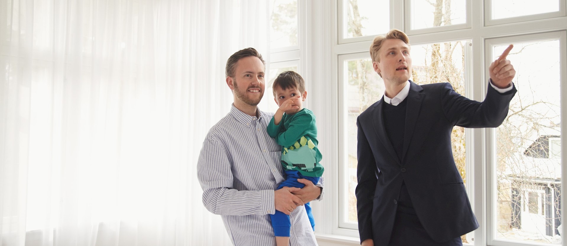 Eiendomsmegler viser mann og sønn rundt i en bolig.