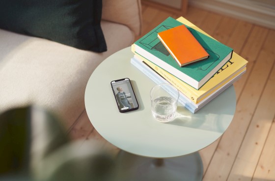 Mobil, bøker og et glass vann står fremme på et bord. Foto.