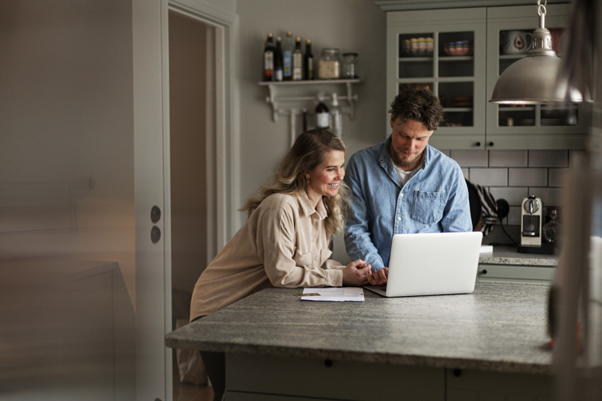 Par ser på boliger på laptop på kjøkkenet